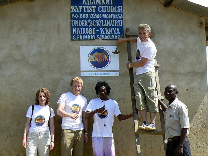 BASIK putting up a sign on a classroom